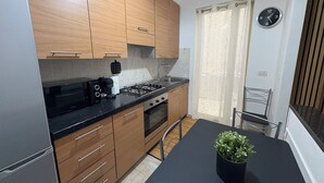 A modern kitchen with wooden cabinets, a gas stove, a coffee maker, and a potted plant on the counter.