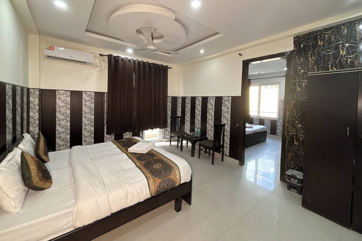Habitación de hotel con cama, escritorio y silla. Se ve un armario y un baño al fondo.