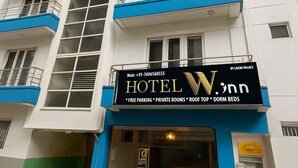 Ein mehrstöckiges Hotel mit Balkonen, einem Schild, das es als Laxmi Palace ausweist, und Annehmlichkeiten wie kostenlose Parkplätze, private Zimmer, eine Dachterrasse und Schlafsäle.