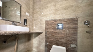 Ein Badezimmer mit Marmorwaschbecken, Toilette und Duschbereich mit Backsteinwand.