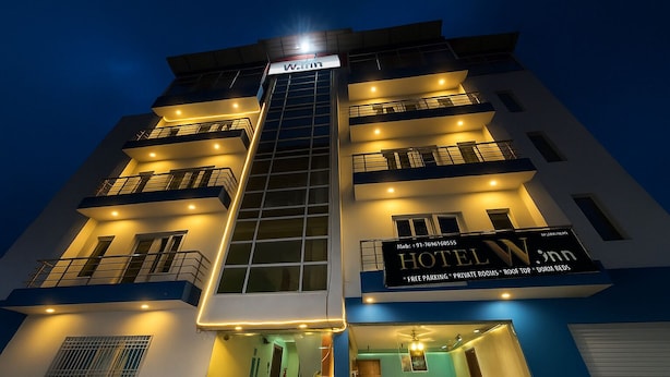 Ein mehrstöckiges Hotel mit einem gut sichtbaren Schild, auf dem "HOTEL Winn" steht. Es verfügt über Balkone, einen Empfangsbereich und ein modernes architektonisches Design.