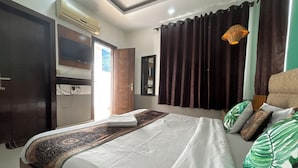 Ein Hotelzimmer mit Bett, Schrank, Deckenventilator, Fenster mit Vorhängen und einer Hängelampe.