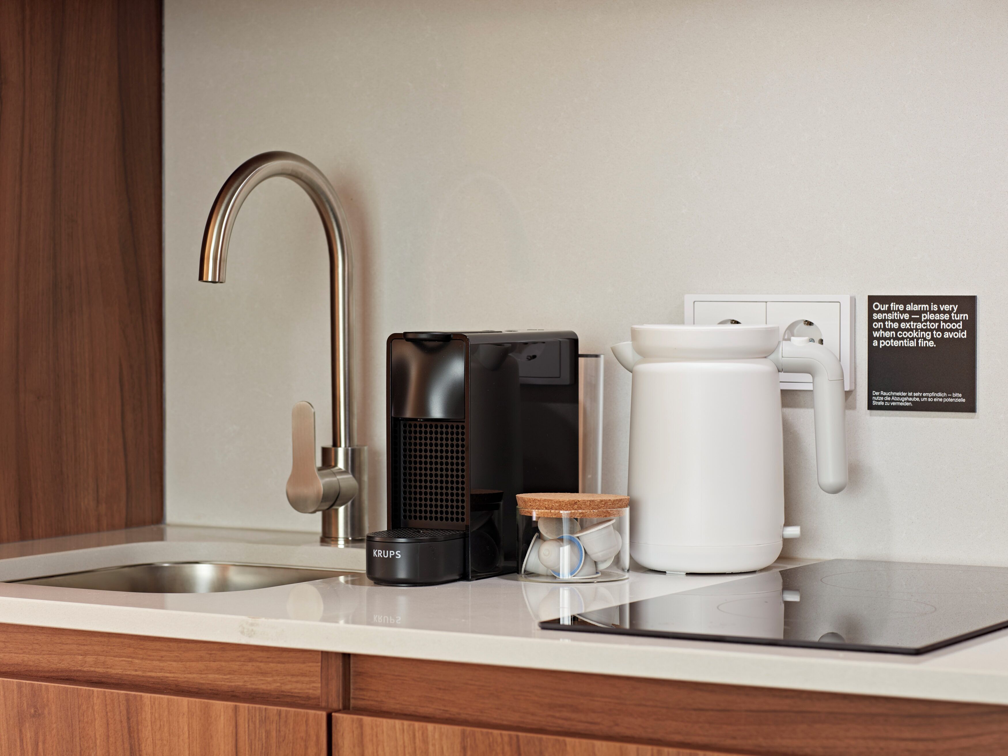 Una cocina moderna con un lavamanos de acero inoxidable, una cafetera y un hervidor en la encimera.