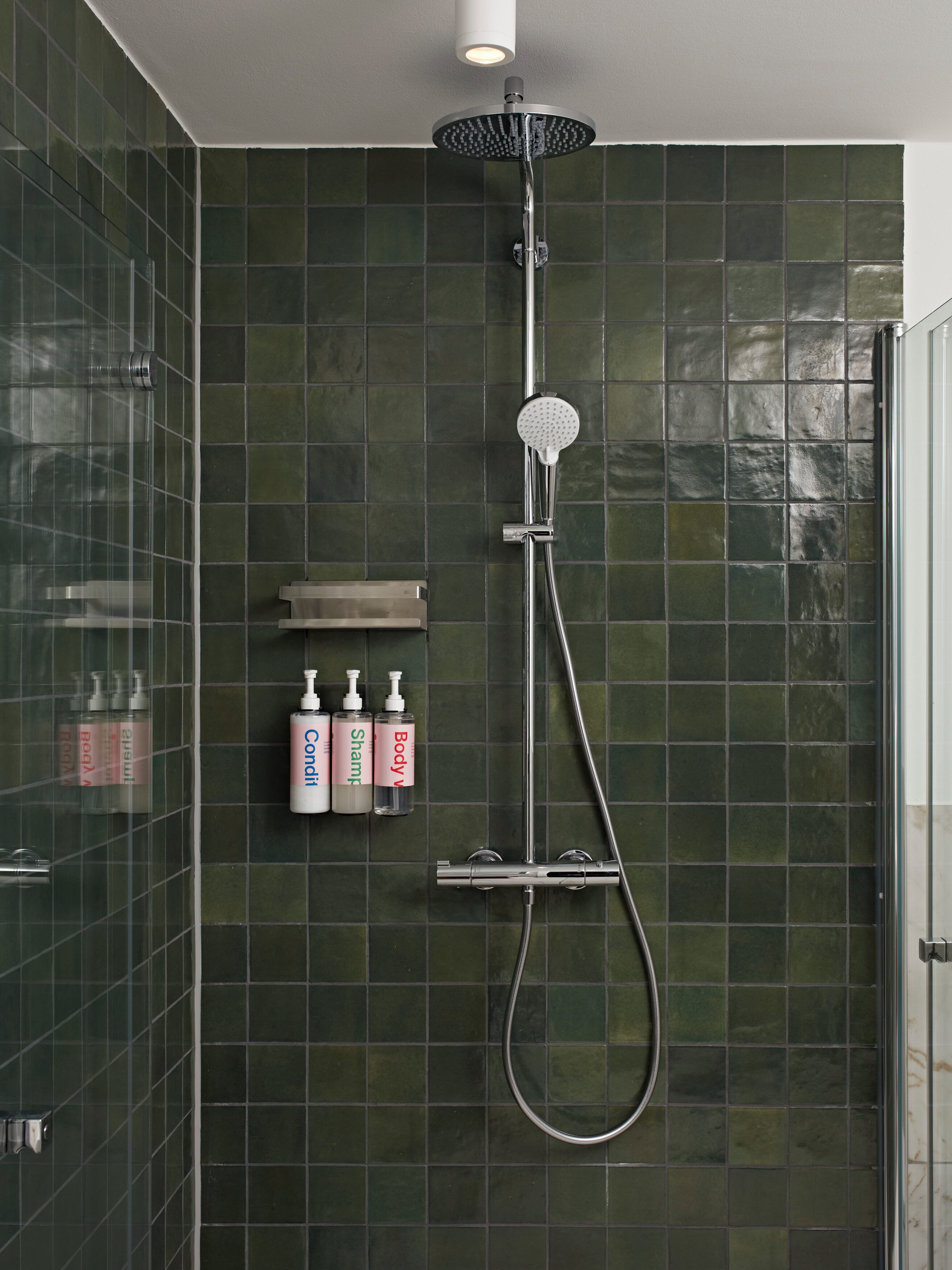 A modern shower with a handheld showerhead and a wall-mounted control panel.