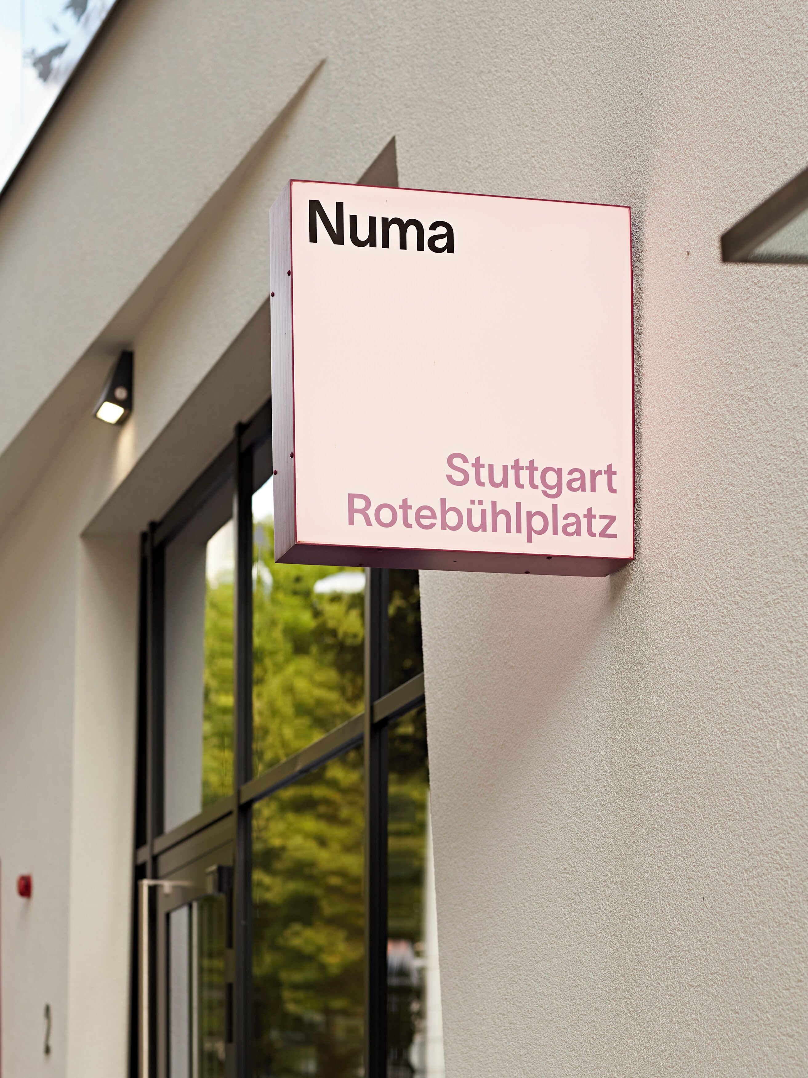 A sign with the name 'Numa' and the address 'Stuttgart Rotebühlplatz' mounted on a building.