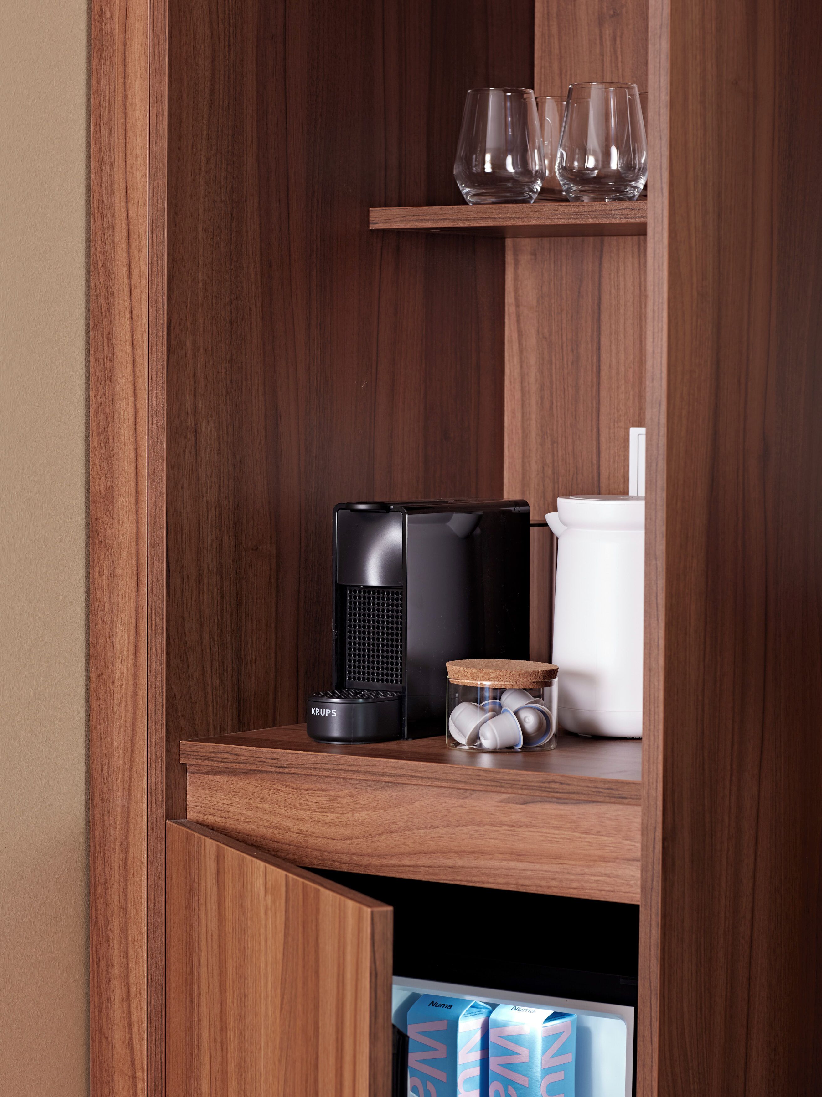 Een houten plank met een koffiezetapparaat, een glazen pot met een kurken dop en een witte bak.