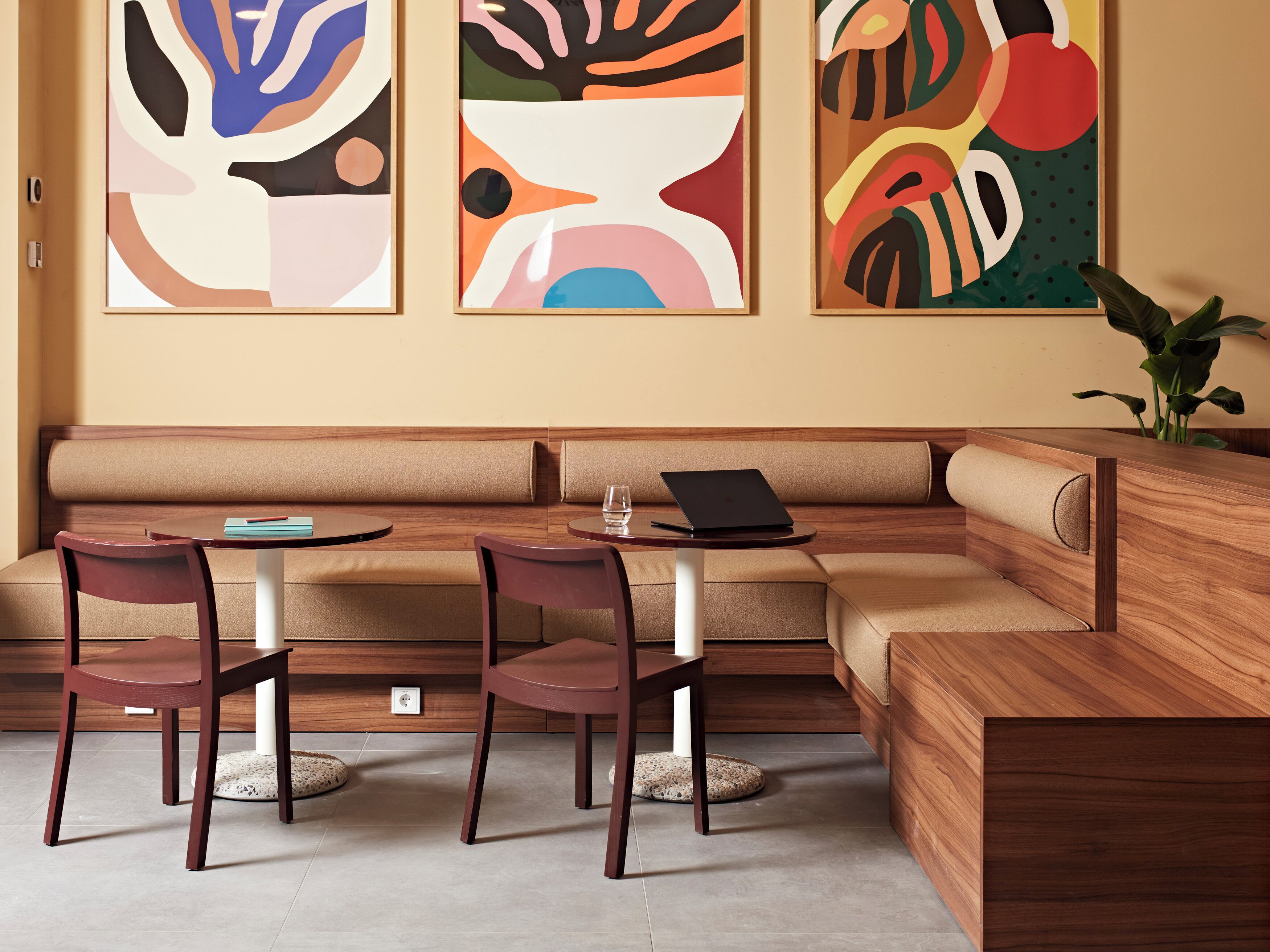Un área de estar moderna con un sofá, dos sillones y una mesita con un ordenador portátil y un vaso.