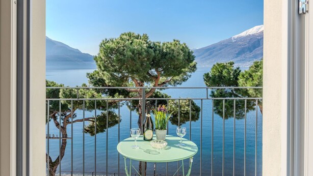 A balcony with a table set for two, overlooking a lake and mountains. - Nice apartment for 6 guests with WIFI, TV, balcony and pets allowed (Domaso)