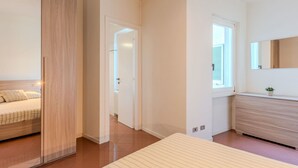 A modern bedroom with a large bed, a wooden wardrobe, and a bathroom with a mirror and window. - Nice apartment for 6 guests with WIFI, TV, balcony and pets allowed (Domaso)