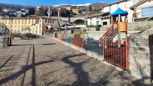 A cobblestone street with a playground and buildings in the background.