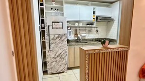 Une cuisine moderne avec des armoires blanches, un plan de travail en marbre et un four encastré.