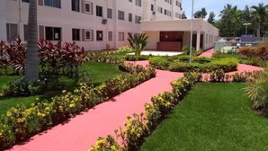 Un hôtel moderne doté d’une cour intérieure, entourée d’une végétation luxuriante et bordée d’un chemin rouge.