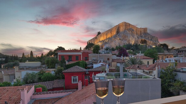 Vista de un paisaje urbano con una colina destacada y un edificio en su cima, con vistas a una zona residencial con casas de tejados rojos.