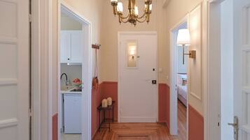 A hallway with a wooden floor, white doors, and a chandelier.