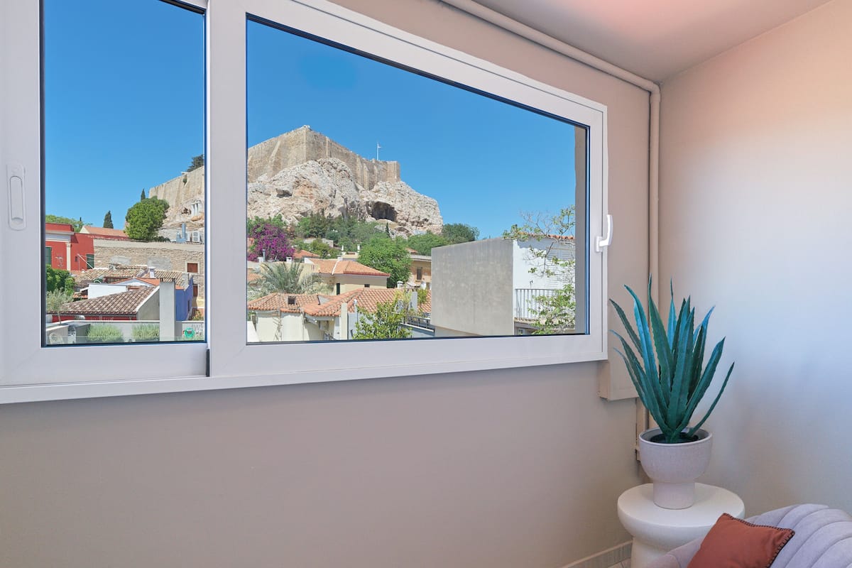 A room with a large window offering a view of a historic building and surrounding houses.