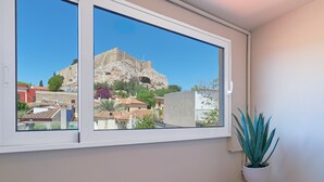 Una habitación con un amplio ventanal que ofrece vistas a un edificio histórico y casas aledañas.