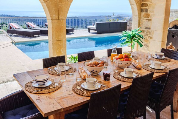 A dining table set with breakfast items, overlooking a pool and lounge area. - Le Mas d’Azur – Exceptional view & pool (Tourrettes-sur-Loup)