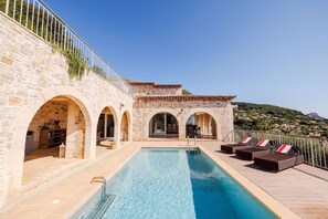 A stone building with a swimming pool, outdoor seating, and a view of the landscape.