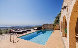 A rooftop pool with lounge chairs and a view of the landscape.