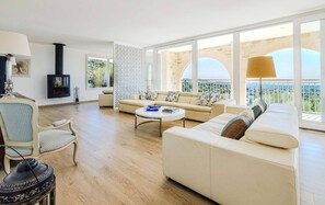 A spacious living room with a large sofa set, a coffee table, and a fireplace. - Le Mas d’Azur – Exceptional view & pool (Tourrettes-sur-Loup)