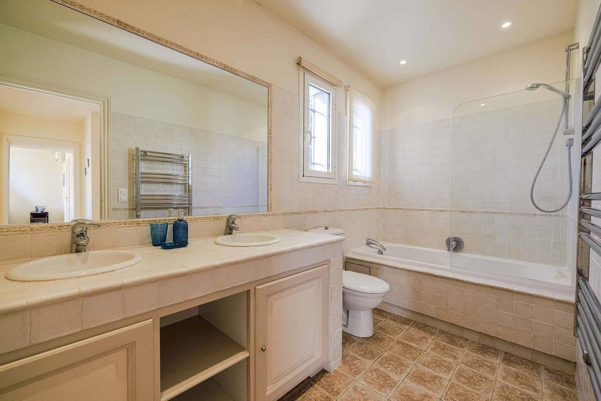 Une salle de bain comprenant un meuble-lavabo à deux vasques, des toilettes, une baignoire et une douche.