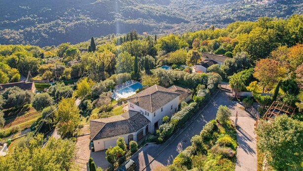 Une villa avec piscine, entourée d’une végétation luxuriante et de collines.