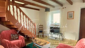 Un salon chaleureux avec un escalier en bois, un téléviseur et un fauteuil en forme de bateau.