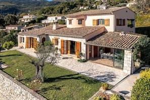 A Mediterranean-style villa with a stone facade, a tiled roof, and a patio with outdoor furniture.