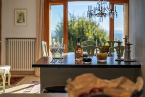 A dining table with a bottle, glasses, and a bowl of snacks.