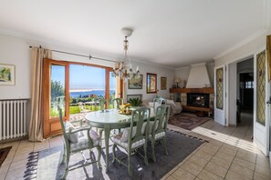A dining area with a table and chairs, a chandelier, and a view of the outdoors. - Villa Virettes – Peaceful haven with pool (Tourrettes-sur-Loup)