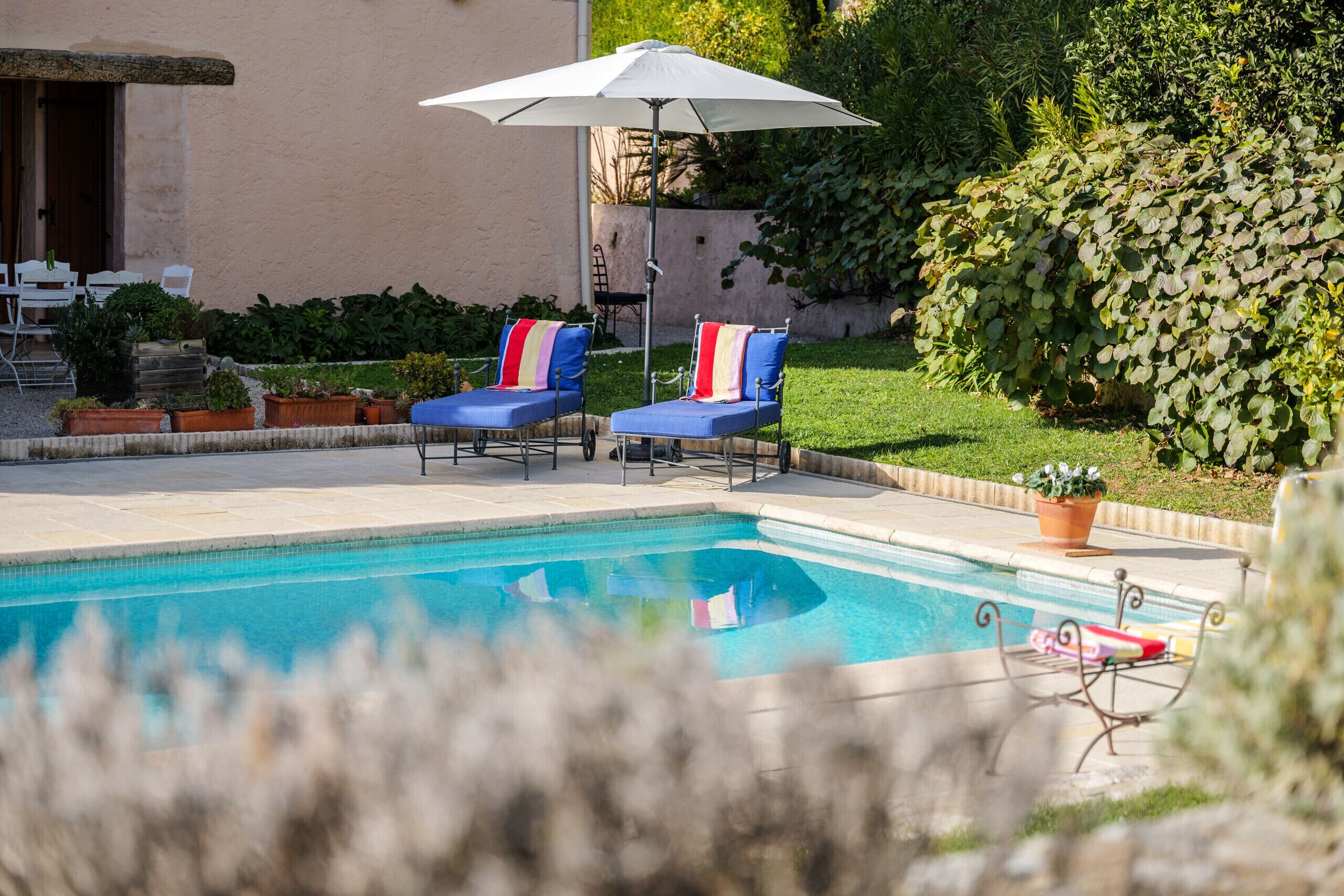 A swimming pool with two lounge chairs and an umbrella.