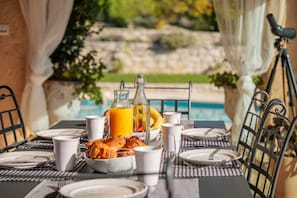 A breakfast table set with plates, cups, a bottle of orange juice, and a bowl of food.