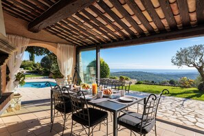 An outdoor dining area with a view of a pool and landscape.