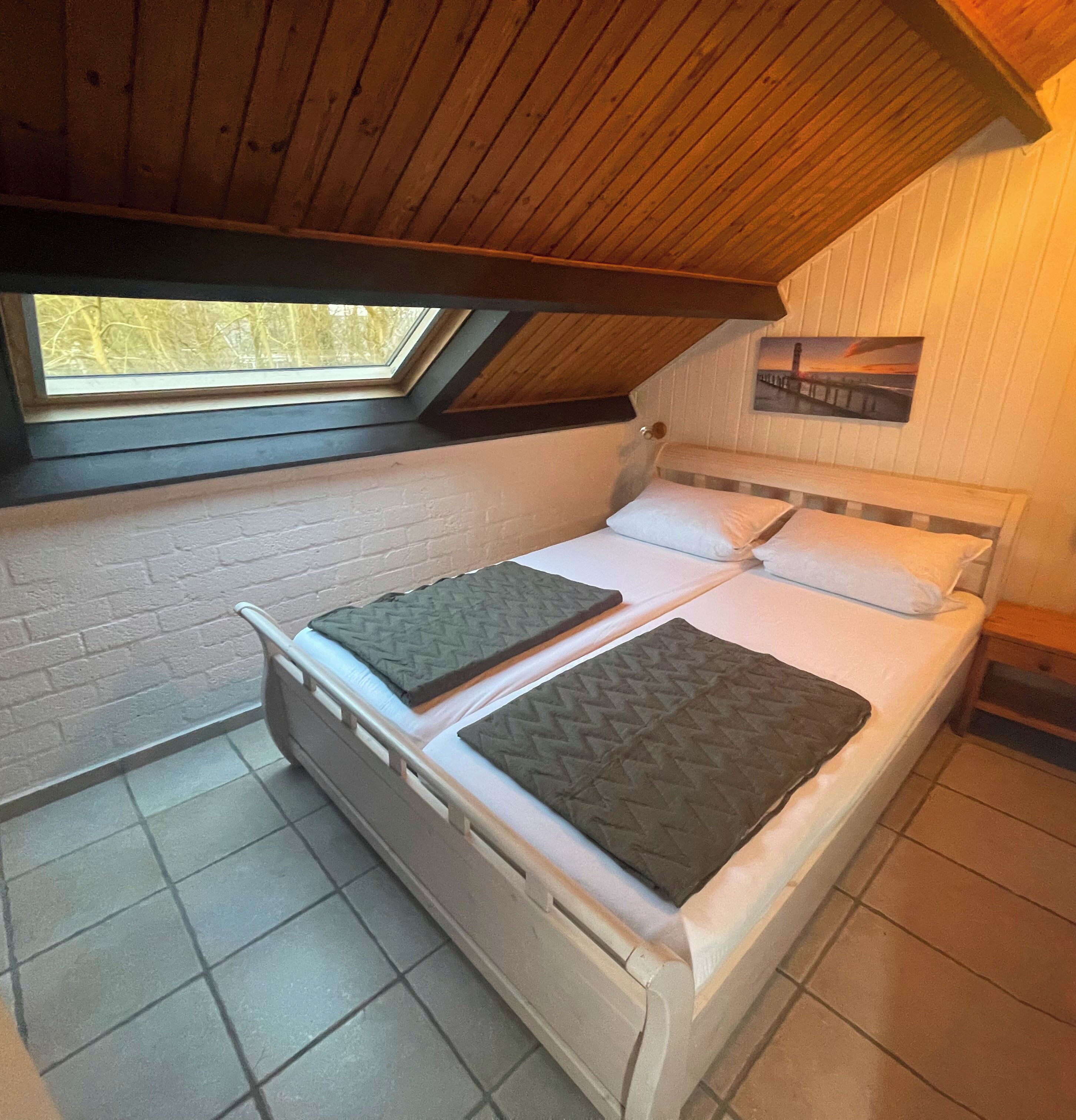 A small, single-bed room with a sloped ceiling and a skylight.
