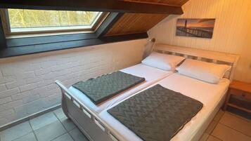 A small, single-bed room with a sloped ceiling and a skylight.