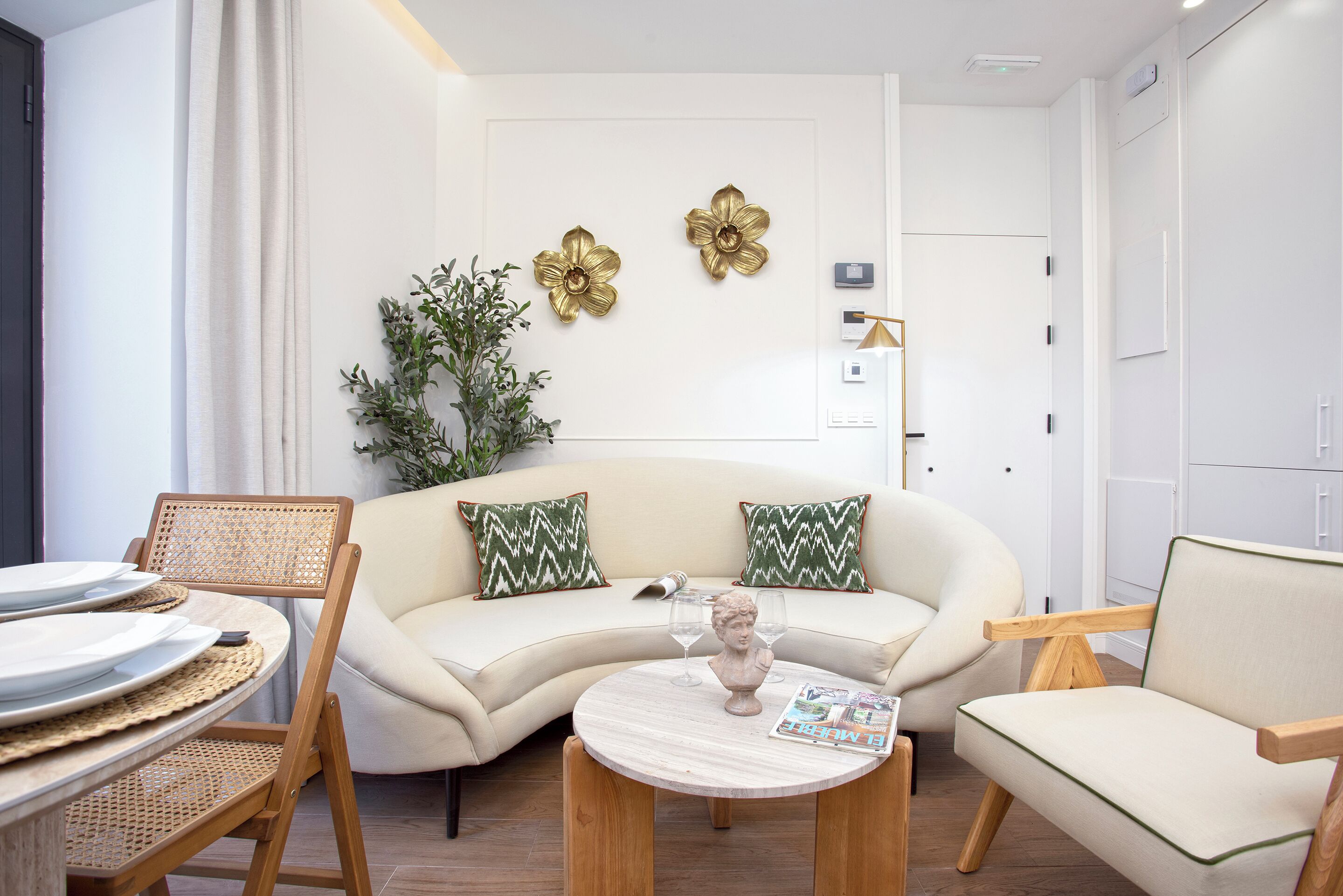 A modern living room with a sofa, two chairs, a coffee table, and decorative elements like a plant and wall art.