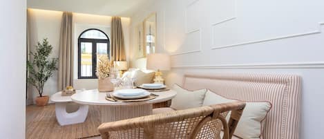 A cozy room with a round table, wicker chair, striped sofa, and a large mirror.