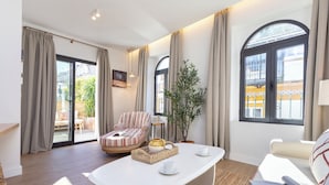 Una sala de estar moderna con un sofá blanco, un sillón a rayas, una mesita de centro con bandeja y una planta en maceta.
