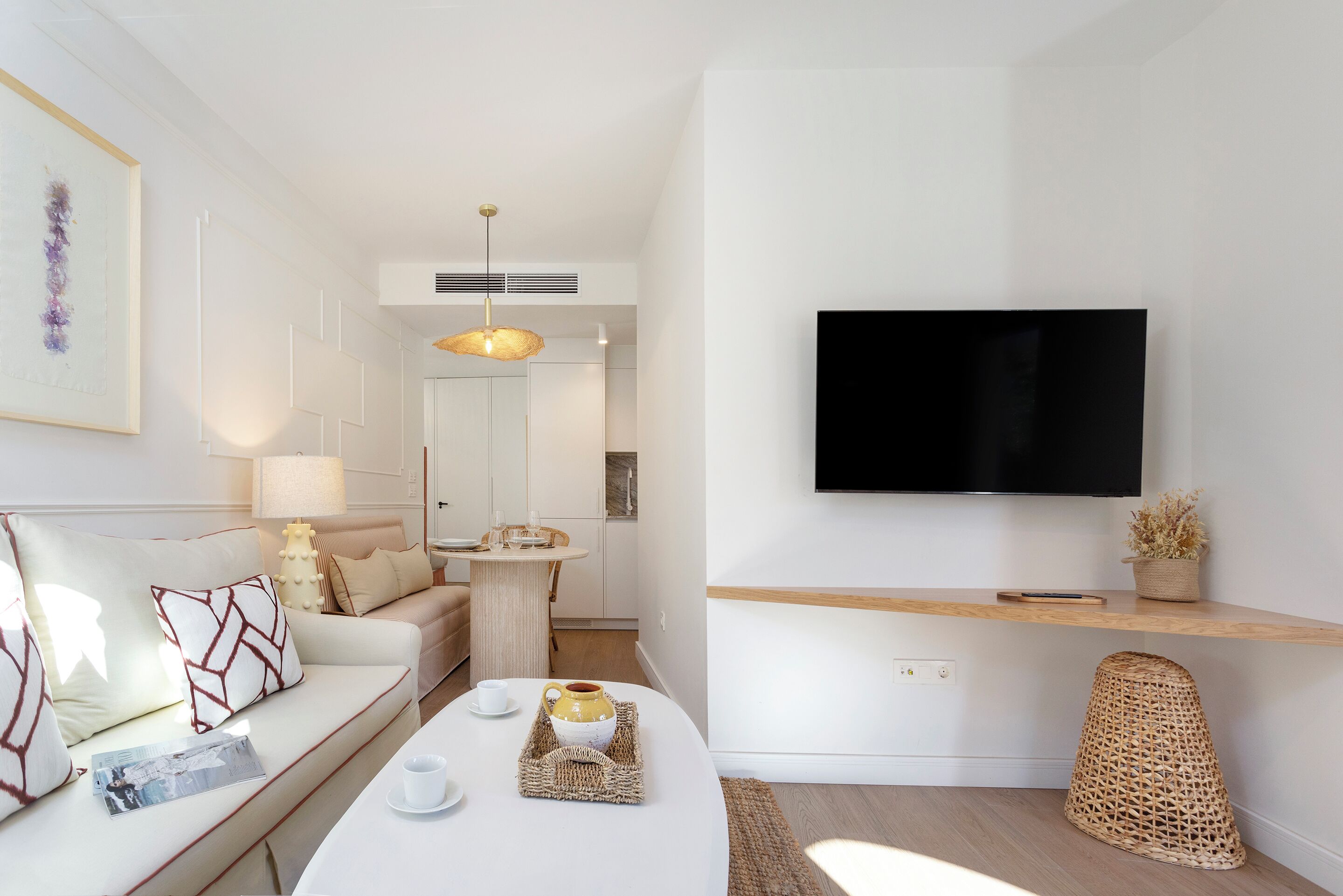 A modern living room with a sofa, coffee table, and a flat-screen TV mounted on the wall.