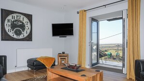 Una sala de estar moderna con un ventanal grande, un televisor de pantalla plana, una mesa de centro de madera y un tapete con estampado de cebra.