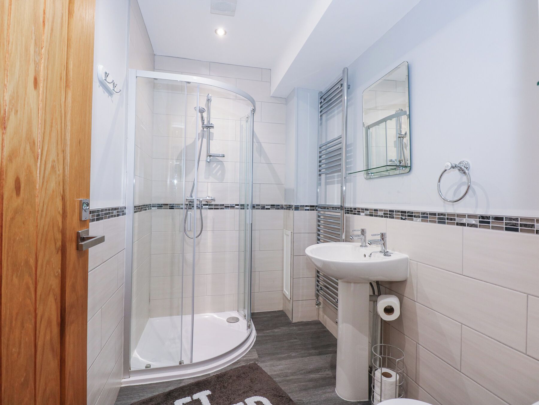 Une salle de bain moderne avec une douche à parois de verre, un lavabo sur colonne et des toilettes.