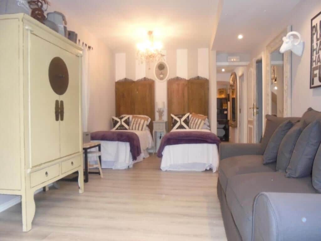 A bedroom with two beds, a wardrobe, and a sofa.