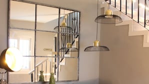 A living room with a grey armchair, a cactus-themed pillow, a floor lamp, and a mirrored wall reflecting a staircase. - TAK Boutique Marbella Old Town with Parking (Marbella)