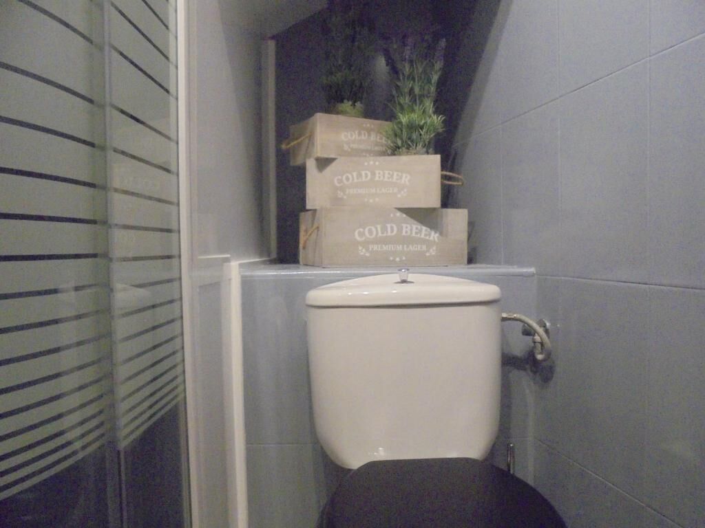 A bathroom with a toilet, a sink, and a set of cold beer boxes stacked on a shelf.