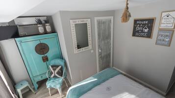 A bedroom with a bed, a turquoise dresser, a chair, and motivational wall art.