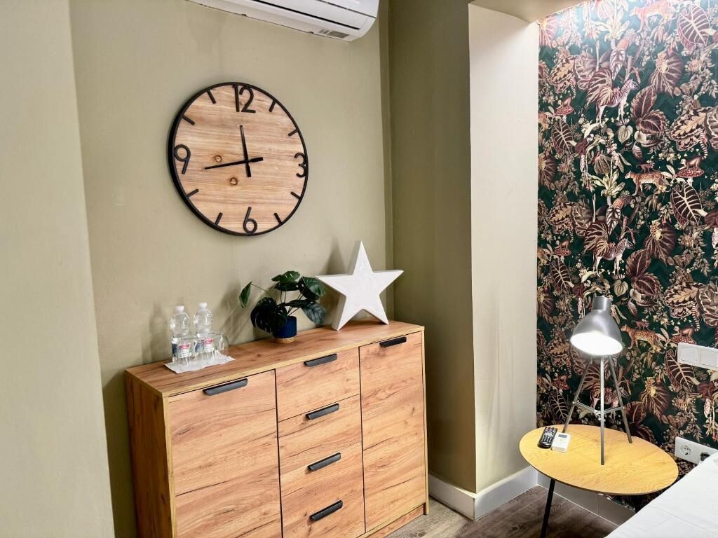 Una habitación con un armario de madera, un reloj de pared, una decoración con forma de estrella, una lámpara y un papel tapiz estampado.