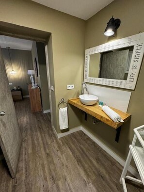 A bathroom with a wooden vanity, a large mirror, and a towel rack. - TAK Boutique Marbella Old Town with Parking (Marbella)