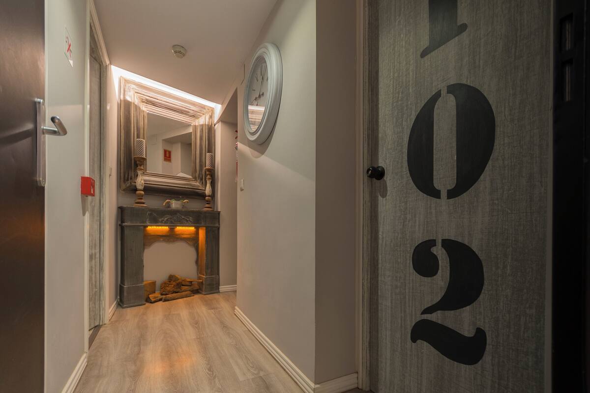 Un pasillo con piso de madera, una chimenea y una puerta con el número 1022.