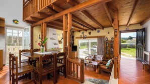 A spacious living area with wooden furniture, a dining table, and a balcony with a view. - Yanni’s Place (93MF+669 Petaloudes, Greece)