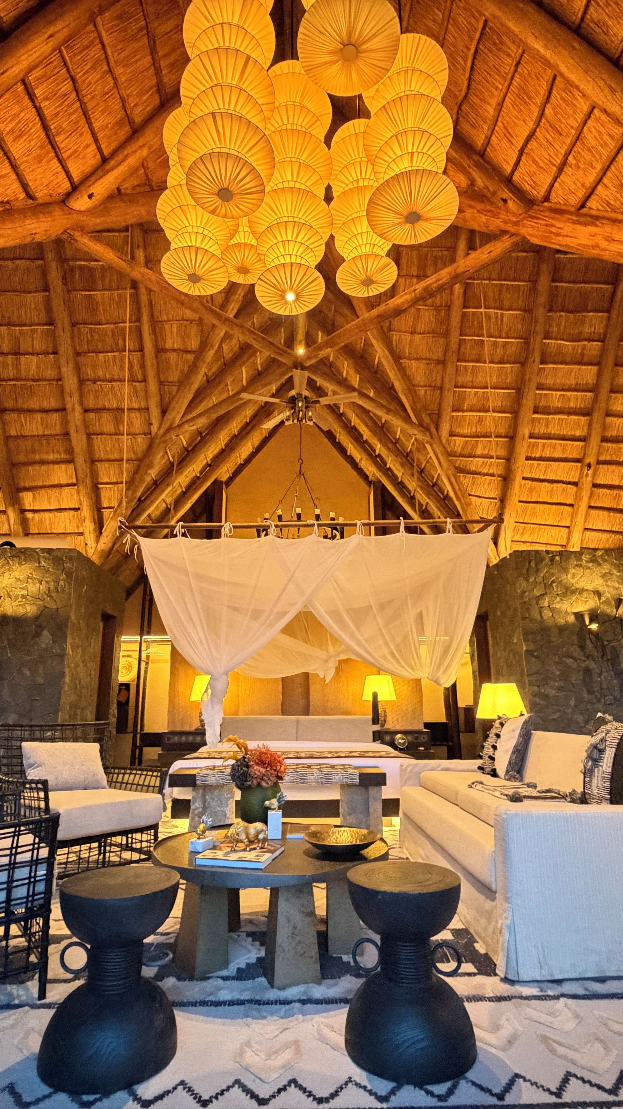 A cozy lounge area with a high ceiling, a central seating arrangement, and a decorative hanging light fixture.